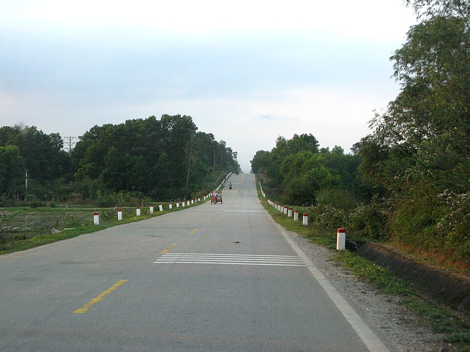 Two-lane paved trunk road with roadside marker posts in rural Viet Nam
